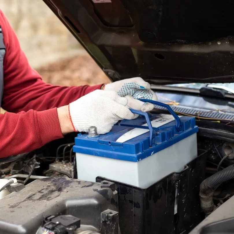 Mavi aküyü motor bölmesine yerleştiren eller