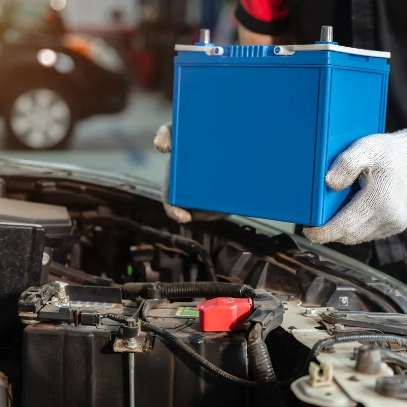 Eldivenli eller mavi aküyü motor bölmesine yerleştiriyor